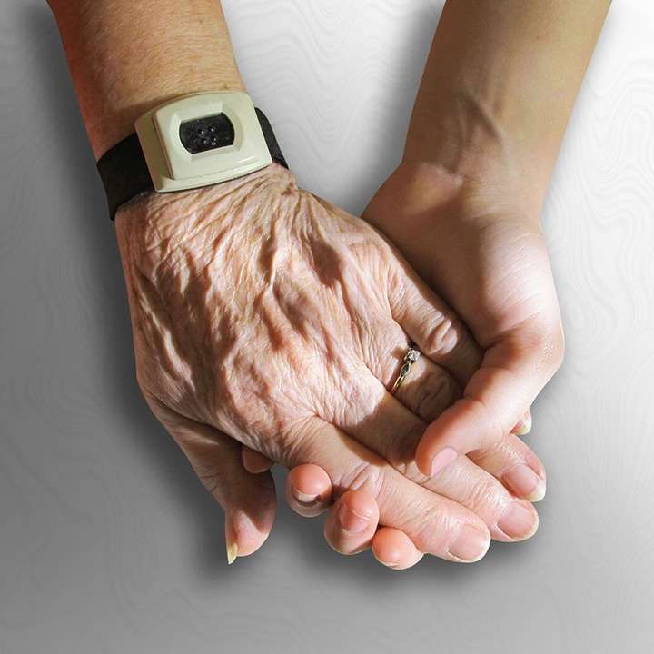 Stock image of a young and old person holding hands